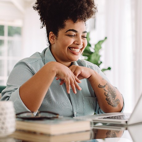 Woman smiling while working on laptop at home