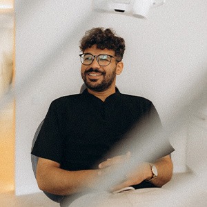 Patient with black glasses smiling in treatment chair