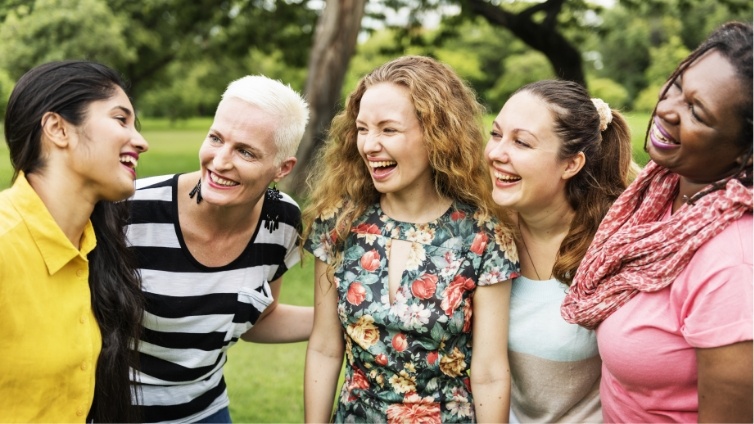 Group of five women laughing together outdoors