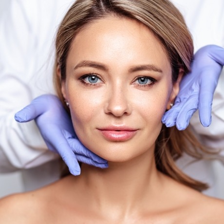 Dentist gesturing to blonde woman smiling in treatment chair