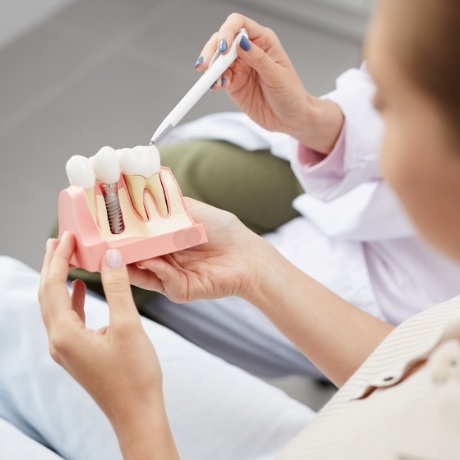 Dentist showing a dental implant model to a patient