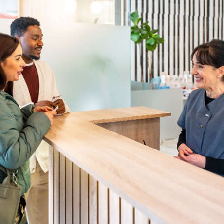 Couple smiling while talking to dental assistant in lobby