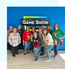 Loretto Family Dentistry team next to sign on wall that says Game Show Battle Room