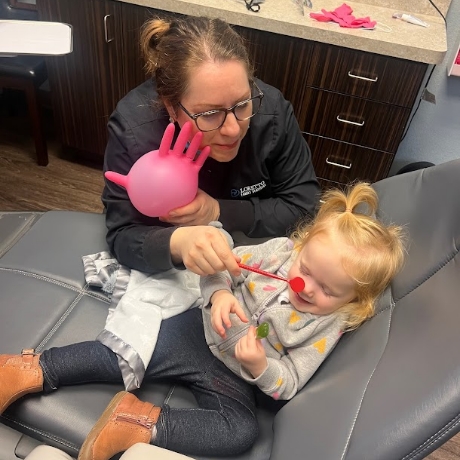 Dental team member showing dental mirrors to a child in the treatment chair