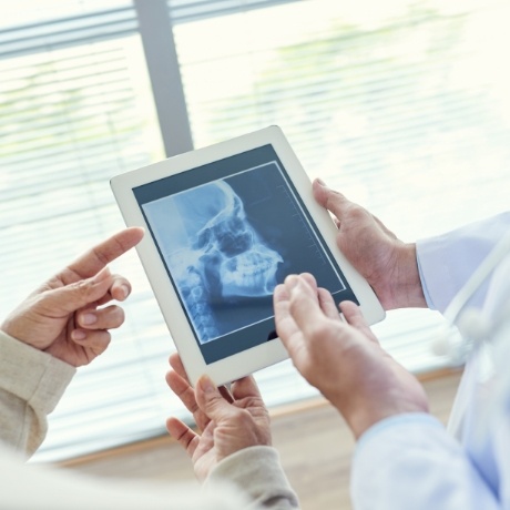 Two dentists looking at x ray of jaw on tablet