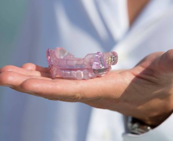 Hand holding a light purple occlusal splint tray