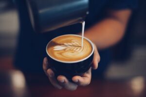 Pouring milk into cup of coffee.